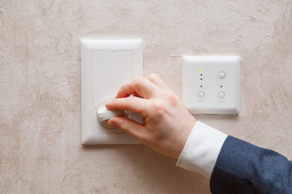 Man regulating temperature on air conditioning controller thermostat on the wall
