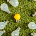 top view of fluorescent lamps near yellow lamp on green grass, energy efficiency concept